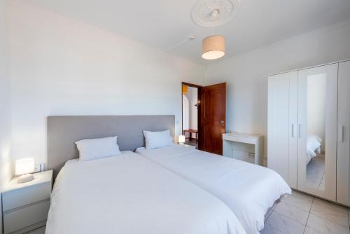 een witte slaapkamer met een groot wit bed met witte lakens bij Solgarve in Quarteira