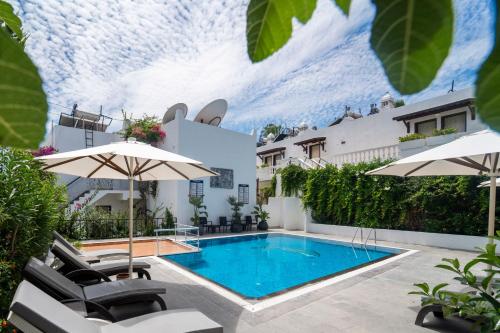 a swimming pool with chairs and umbrellas on a patio at Manuela Boutique Hotel Bitez in Bitez