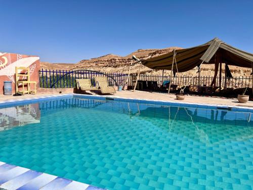 a large swimming pool with chairs and a tent at Dar Salwa in Aït Ben Haddou