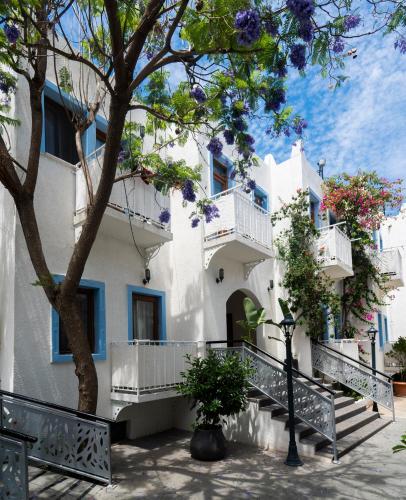 a white building with balconies and a tree at Manuela Boutique Hotel Bitez in Bitez