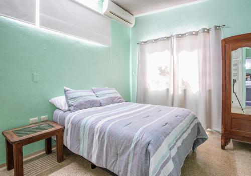 a bedroom with a bed with a table and a window at Villa privada en Chuburná in Mérida