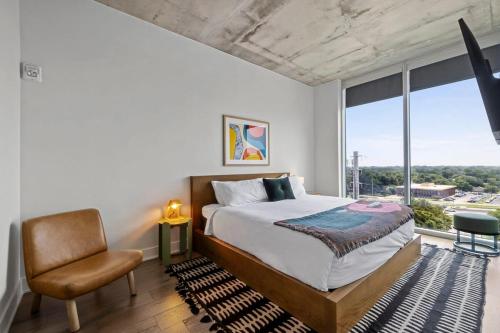 a bedroom with a bed and a chair and a window at Modern 1BR Condo on Rainey St with Pool and Views in Austin