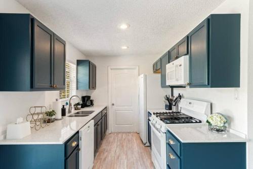 una cocina con armarios azules y electrodomésticos blancos en Charming East Side Bungalow, en Austin