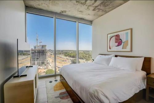Un dormitorio con una cama grande y grandes ventanales. en High Rise in the heart of ATX, en Austin