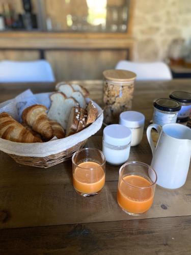een tafel met een broodmand en twee glazen sinaasappelsap bij La Dame Jeanne in Fontanès