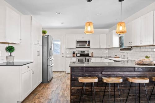 a kitchen with white cabinets and a large island with bar stools at Leisure Escape - TX Hill Country in Dripping Springs