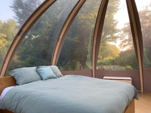 un lit dans une chambre avec une grande fenêtre dans l'établissement Bulle insolite Wigwam, à Aulnay-sur-Iton