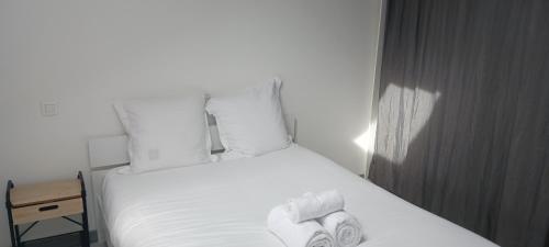 une chambre avec un lit avec des draps blancs et des oreillers dans l'établissement Les petits cosy, à Nancy