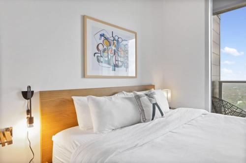 a bedroom with a bed with white sheets and a window at Luxe Condo in Downtown Austin in Austin