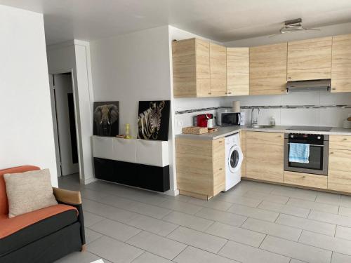 une cuisine avec des placards en bois et un lave-linge dans l'établissement Appartement aux portes de Paris, à Créteil