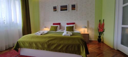 a bedroom with a large bed with green sheets and red pillows at Arianna Apartman in Miskolc