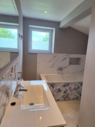 une salle de bain avec un lavabo et une baignoire dans l'établissement La maison de Carine et Didier, à Godewaersvelde