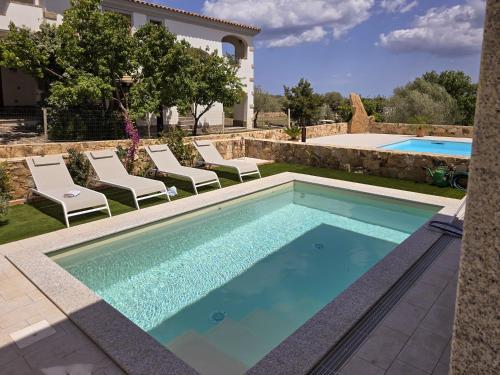 a pool in a backyard with chairs and a house at La Casa di Emy in Budoni