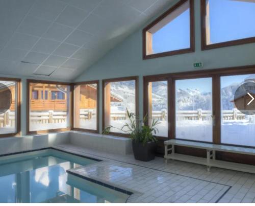 - une grande piscine dans une pièce dotée de fenêtres dans l'établissement Chalet des evettes, à Flumet