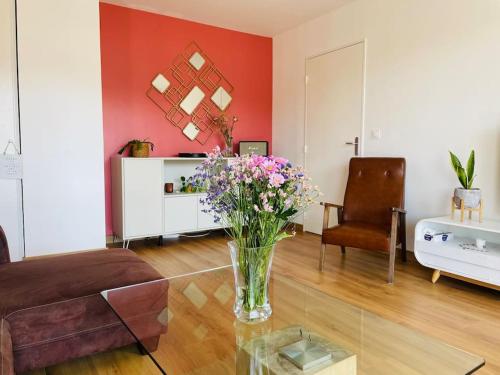 a living room with a vase of flowers on a table at Spacious Near Center Terrace et Parking in Rennes
