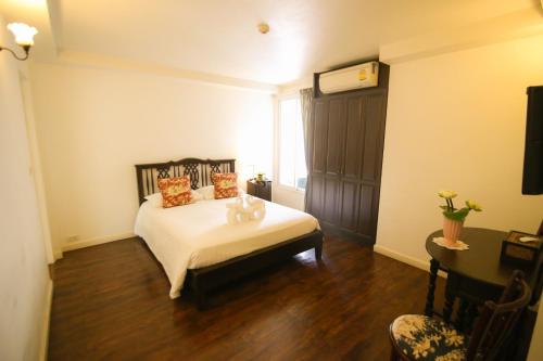 a bedroom with a bed with white sheets and orange pillows at SSIP Boutique Dhevej Bangkok in Bangkok