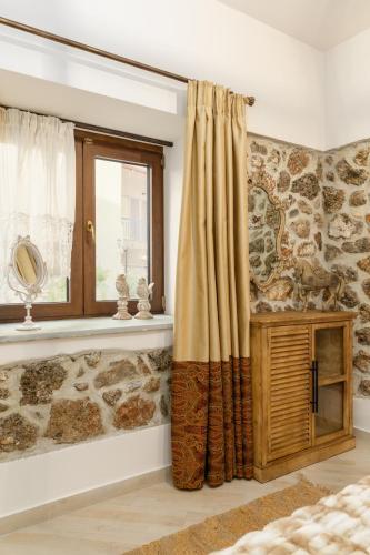 a bedroom with a stone wall and a window at Meydani Suites in Litochoro