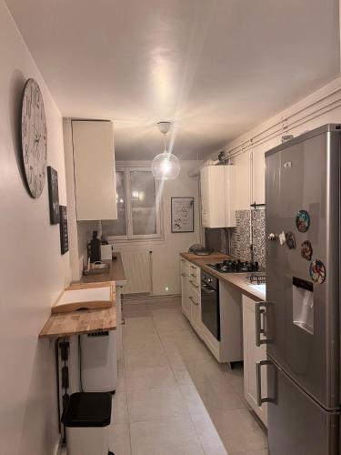 une cuisine avec un réfrigérateur en acier inoxydable et des armoires blanches dans l'établissement Charmant Appartement, à Montmagny