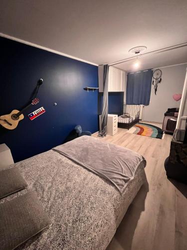 - une chambre avec un lit et une guitare sur le mur dans l'établissement Charmant Appartement, à Montmagny