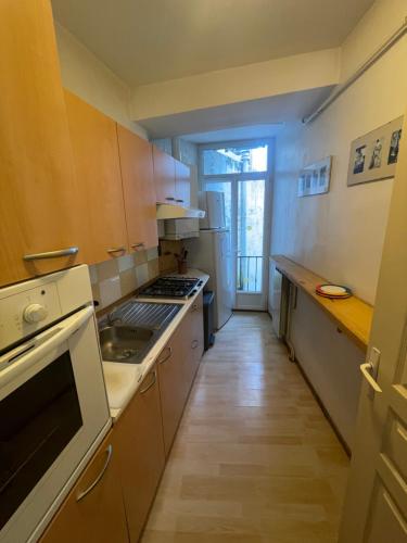 une cuisine avec des armoires en bois et un four à plaques de cuisson dans l'établissement Les Platanes - Renoir Rez de chaussée, à Lamalou-les-Bains