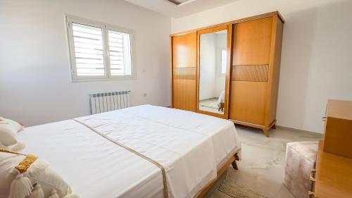 a bedroom with a large white bed and a wooden cabinet at Jasmin Villas Djerba in Mezraya