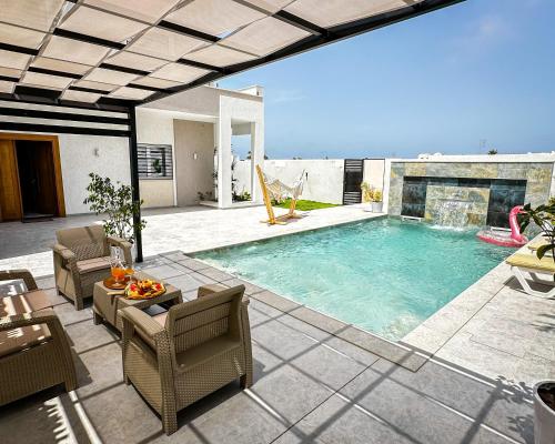 a swimming pool in a patio with chairs and a table at Jasmin Villas Djerba in Mezraya