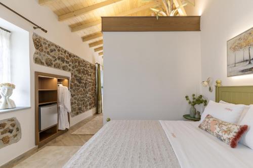 a bedroom with a white bed and a stone wall at Meydani Suites in Litochoro