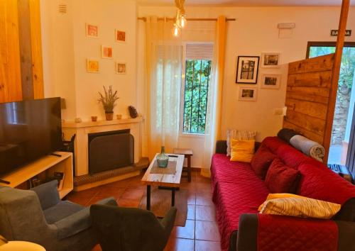 a living room with a red couch and a tv at La Casa Junto al Sendero del Río & Piscina # aire acondicionado in Los Romeros