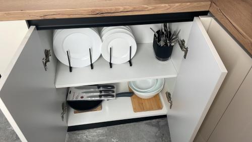 a kitchen cabinet with plates and utensils in it at Studio Ermanos in Curtea de Argeş