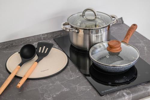 a stove with a pot and utensils on a counter at Five Business-class rooms in R-house near Mega Center Almaty in Almaty