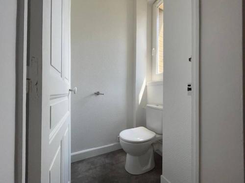 une salle de bain blanche avec toilettes et fenêtre dans l'établissement Spacieux T4 avec grande cuisine Pradelle RDV, à Clermont-Ferrand