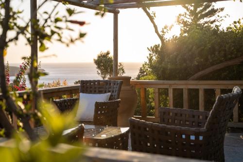 a table and chairs on a deck with the ocean in the background at Terra Minoika Boutique Resort in Káto Zákros