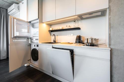 a kitchen with white cabinets and a washer and dryer at HONEST Ricany in Ricany