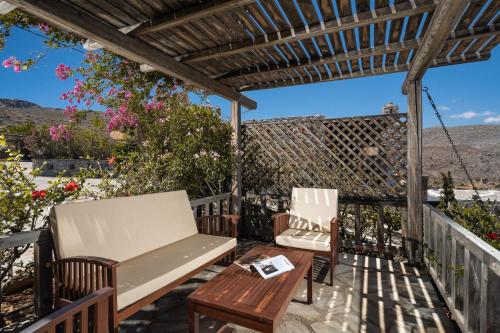 two chairs and a table on a deck with a pergola at Terra Minoika Boutique Resort in Káto Zákros