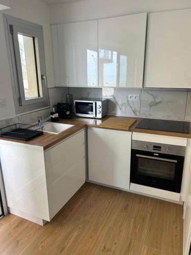 une cuisine avec des armoires blanches, un évier et un micro-ondes dans l'établissement Apparemment bord de mer, à Canet