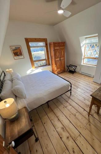 a bedroom with a large bed and a wooden floor at Maison du Havre Grand Duplex in La Malbaie