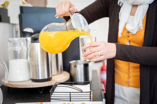 a woman pouring orange juice into a blender at Casa Dona Edite Guesthouse Douro in Vilarinho de Cotas