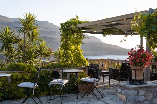 a patio with chairs and tables and a view of the water at Terra Minoika Boutique Resort in Káto Zákros