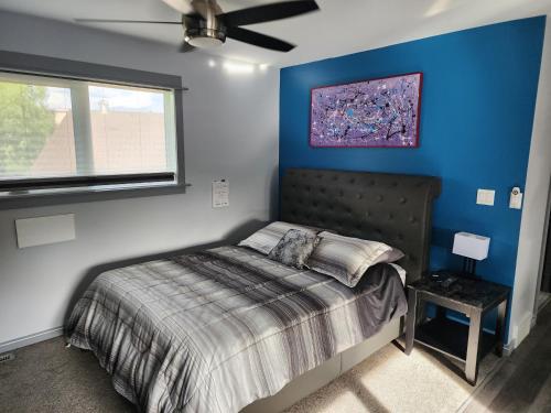 a bedroom with a bed with a blue wall at Loft with Patio & Hot tub in Lethbridge