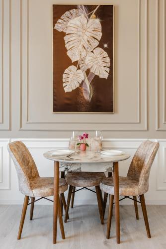 a dining room with a table and chairs and a painting at Five Business-class rooms in R-house near Mega Center Almaty in Almaty