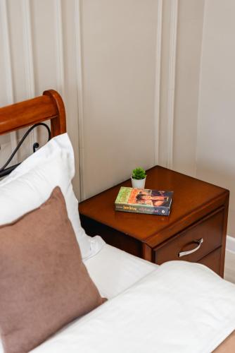 a bed with a night stand next to a table with a book at Five Business-class rooms in R-house near Mega Center Almaty in Almaty