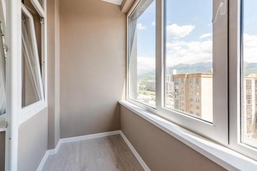 a room with two windows with a view of a city at Five Business-class rooms in R-house near Mega Center Almaty in Almaty