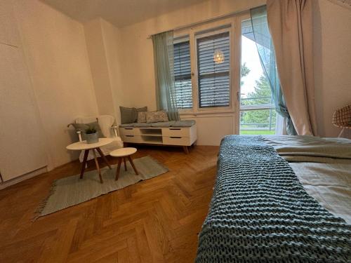 a bedroom with a bed and a table and a window at Madarász 3 Deluxe Vendégház in Balatonalmádi