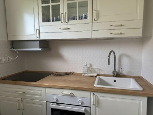 a kitchen with white cabinets and a sink at Madarász 3 Deluxe Vendégház in Balatonalmádi