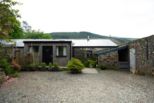 a stone house with a yard with potted plants at Fyne Byre Cottage - Barn Conversion with Hot Tub in Cairndow