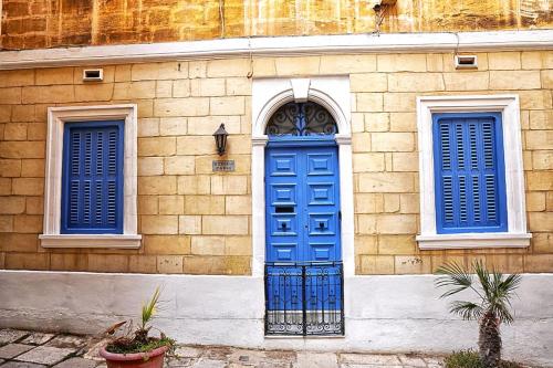 a building with a blue door and two windows at Charming Ground-floor Maisonette in Birgu