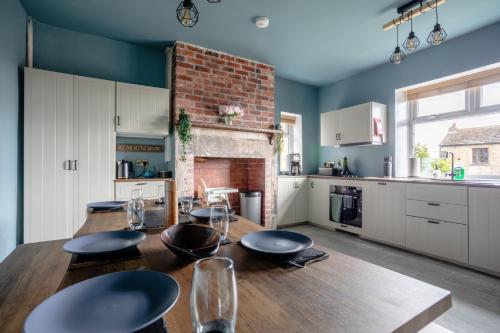 a kitchen with a wooden table and a fireplace at Holmfield House in Clayton West