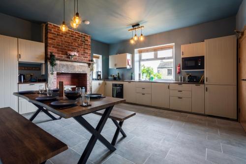 a kitchen with a wooden table and a fireplace at Holmfield House in Clayton West