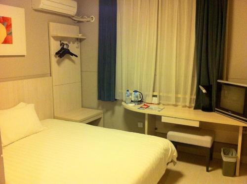 a hotel room with a bed and a desk and a television at Jinjiang Inn Xiamen North Railway Station Jiageng Sports Stadium in Xiamen