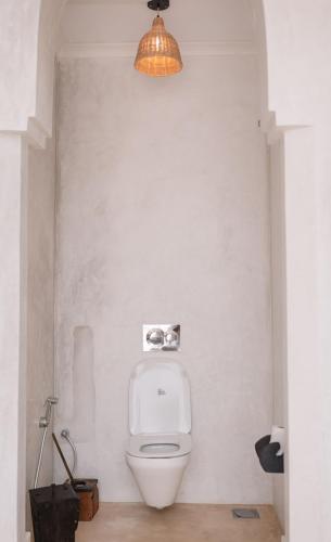 a bathroom with a toilet with a light above it at Royal Cliff Zanzibar in Zanzibar City